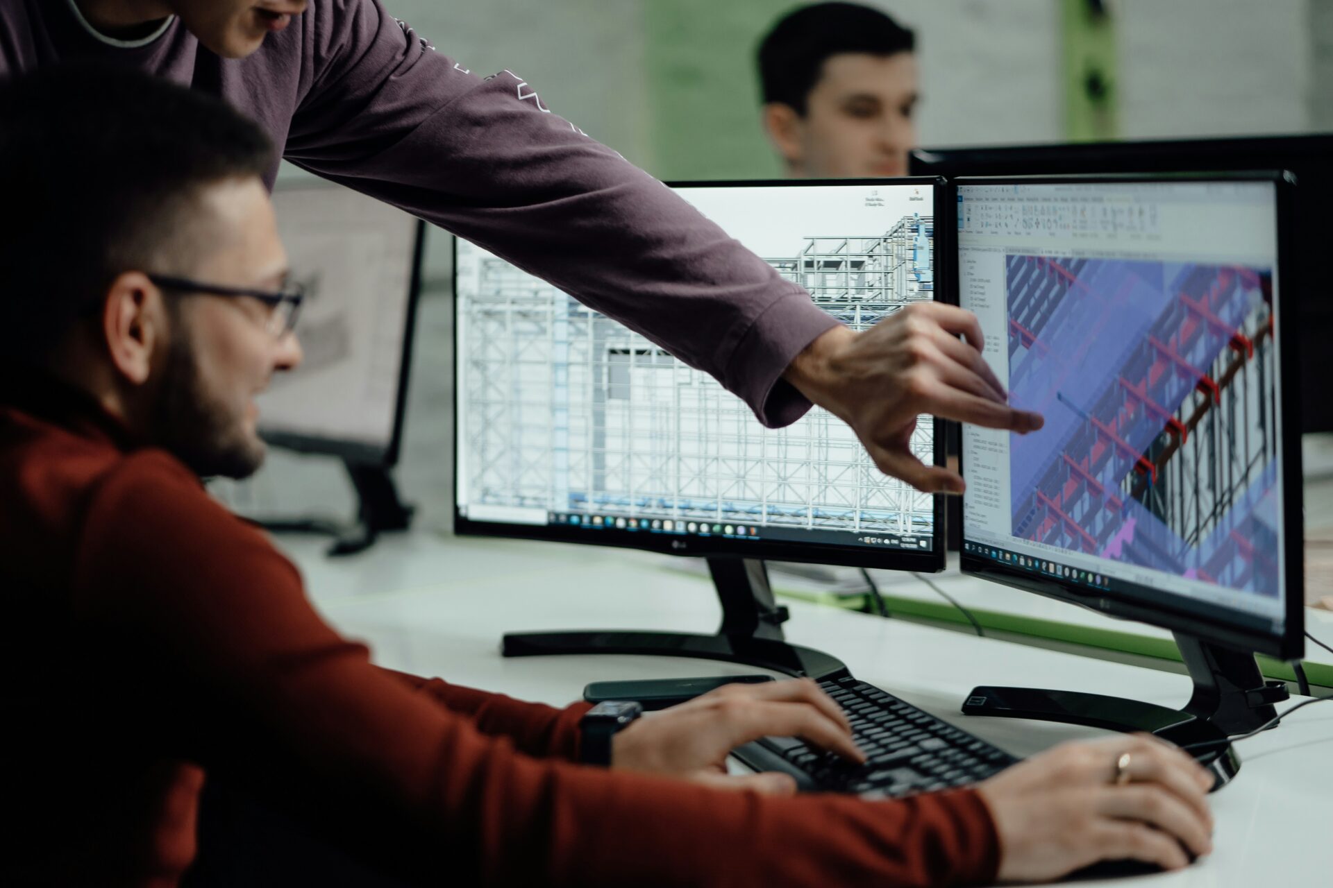 Collaboration autour de la maquette numérique BIM Deux professionnels travaillent sur un modèle numérique de bâtiment en utilisant des logiciels BIM sur double écran