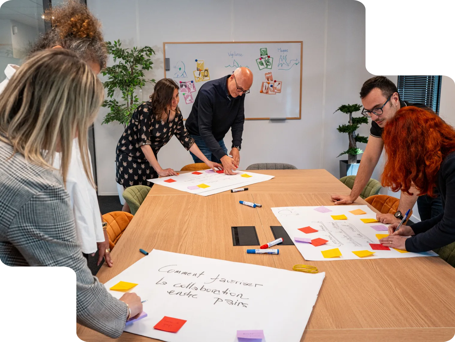 Des apprenants co-créant des solutions sur une table avec des affiches et des notes.