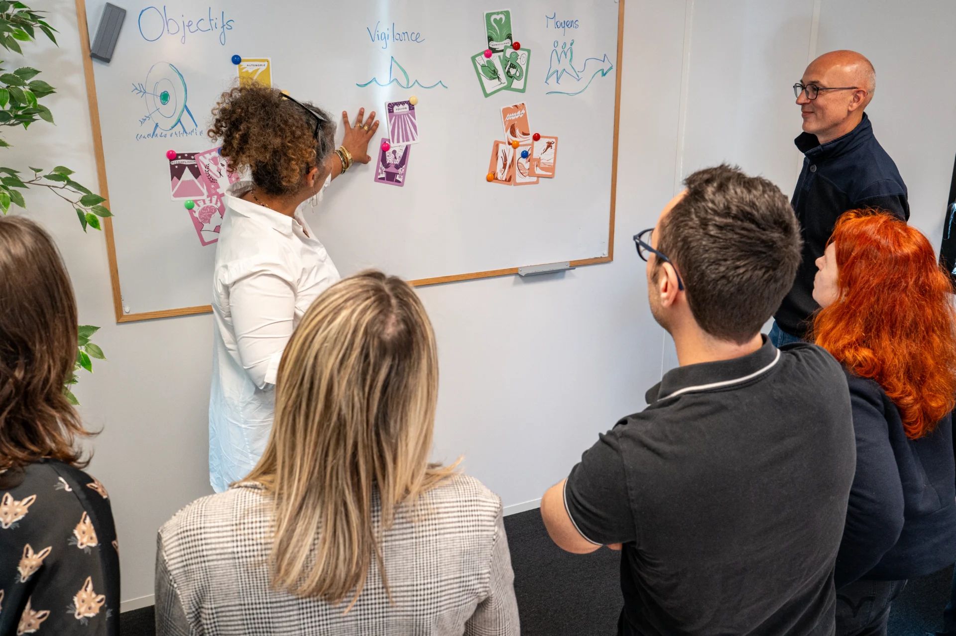 Dynamisez vos formations avec des méthodes pédagogiques interactives. Animation pédagogique en groupe avec une formatrice utilisant des cartes visuelles pour expliquer des concepts.