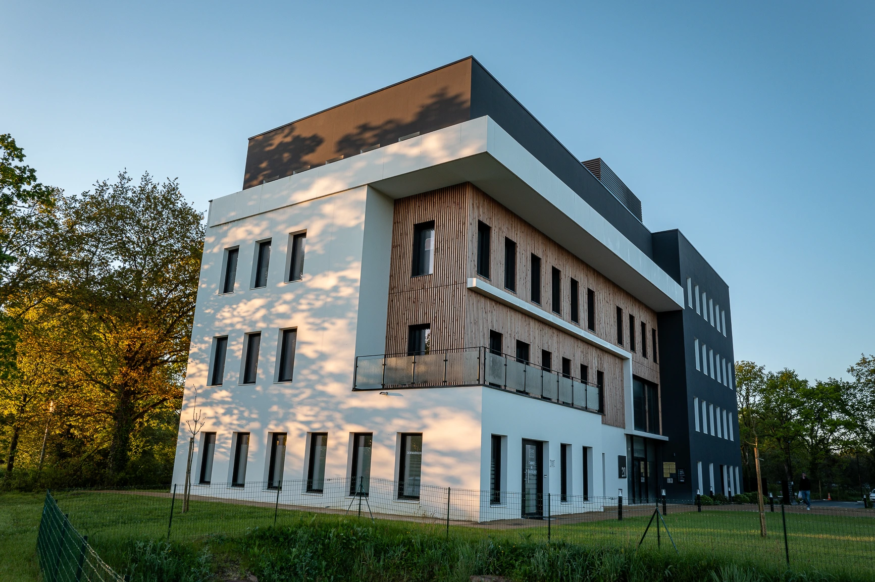 Bâtiment moderne en bois et béton sous une lumière dorée, idéal pour la retouche photo immobilière.