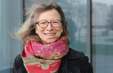Dominique, apprenante souriante en manteau noir et écharpe colorée, formée chez Formalisa.