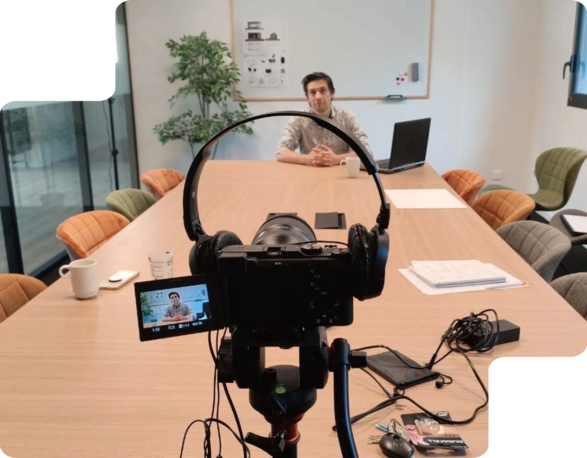 Un formateur est filmé dans une salle de réunion avec une caméra sur trépied, prêt à enregistrer une vidéo pédagogique