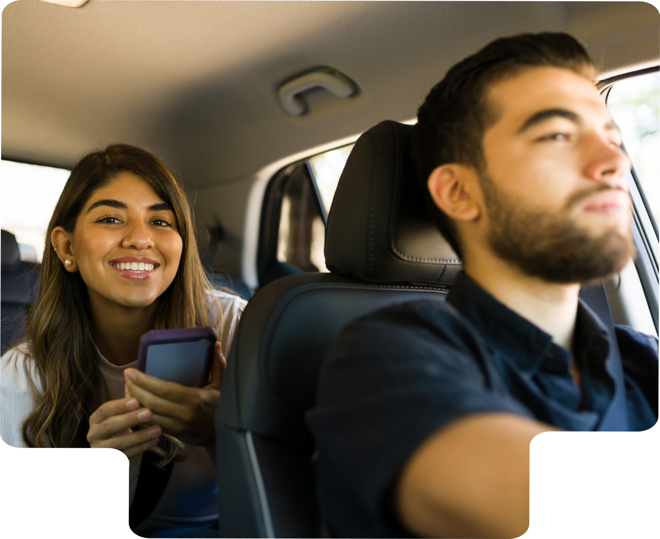 Covoiturage et mobilité durable Jeune femme souriante en covoiturage assise à l’arrière d’une voiture, tenant son téléphone, aux côtés d’un conducteur.