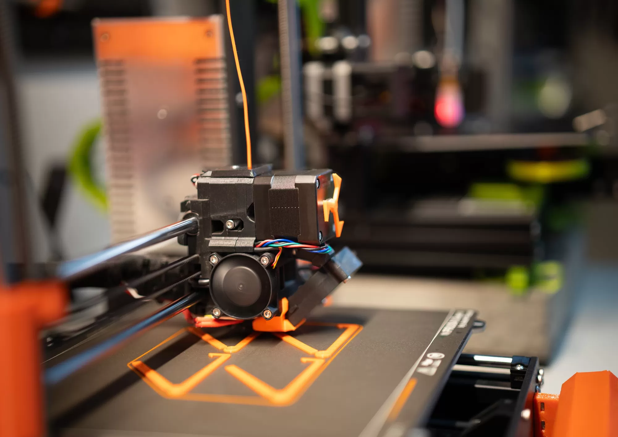 Imprimante 3D en train d’imprimer une pièce en filament orange, illustration d’une formation FreeCAD et modélisation 3D