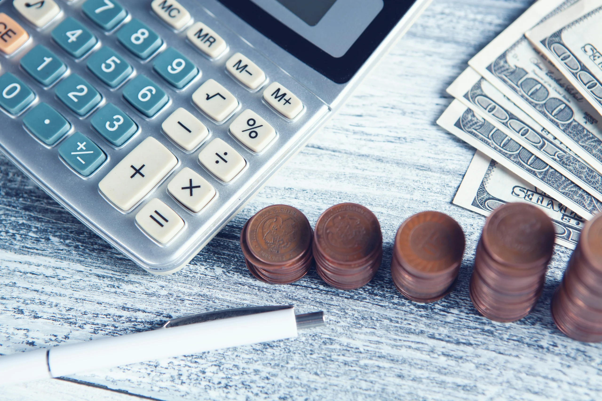 Calculatrice, pièces empilées et billets disposés sur un bureau — illustration du financement de la formation professionnelle